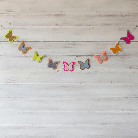 Handmade colourful felt butterfly garland against a white wooden backdrop