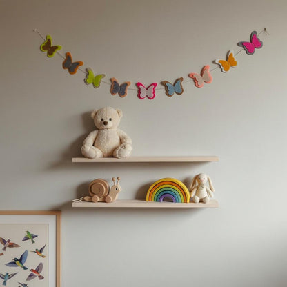 Handmade felt butterfly garland styled above nursery shelves and wooden toys