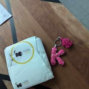 Cecilia’s customer photo of Toddle Paws packaging and a pink initial keychain